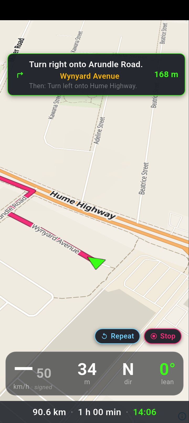 The navigation screen: a turn card reading Turn right onto Arundle Road with Wynyard Avenue underneath in amber and 168 m in green, a Then line naming the turn after it, the Repeat and Stop buttons, the four readouts and a bottom strip reading 90.6 km, 1 h 00 min and an arrival time.